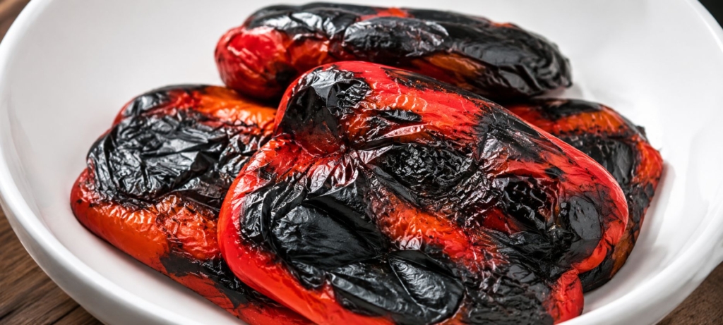 Charred red bell peppers in a white bowl.