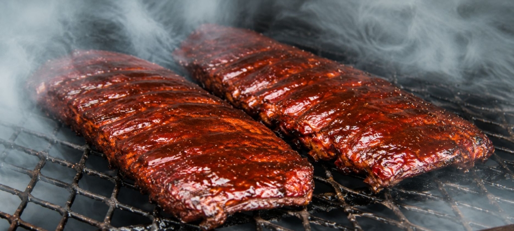 Two racks of apple butter BBQ sauce glazed ribs on a smoker.