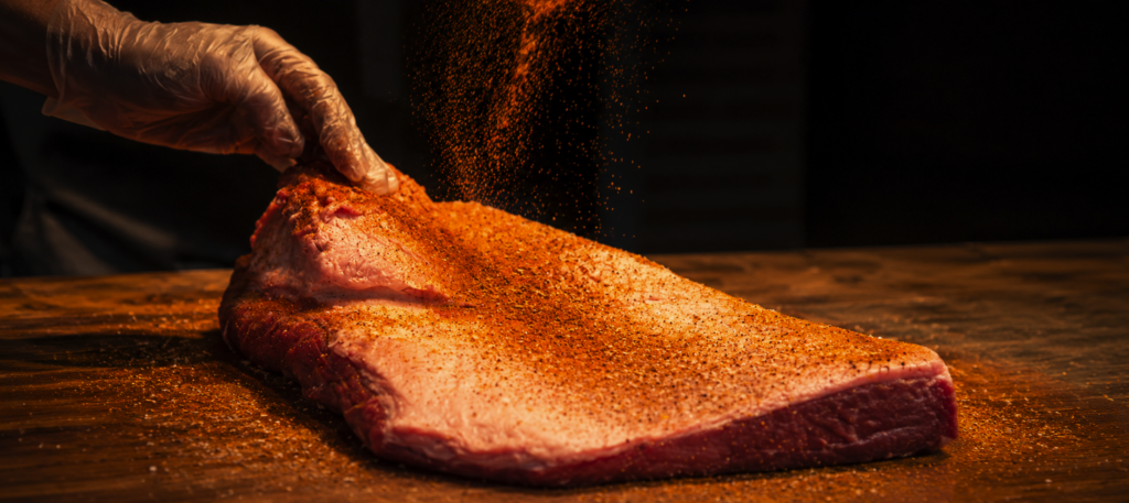 Beef dry rub recipe being sprinkled on to brisket