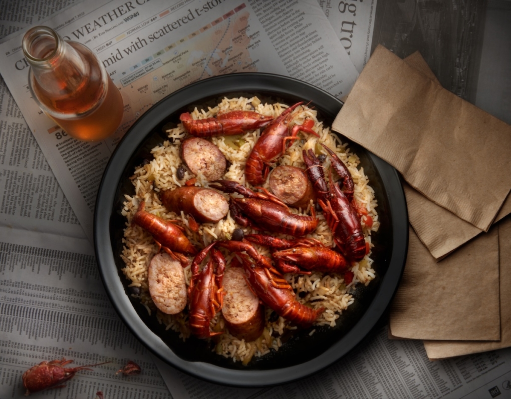 Smoked Dirty Rice Crayfish with sliced sausage in a bowl on a table.