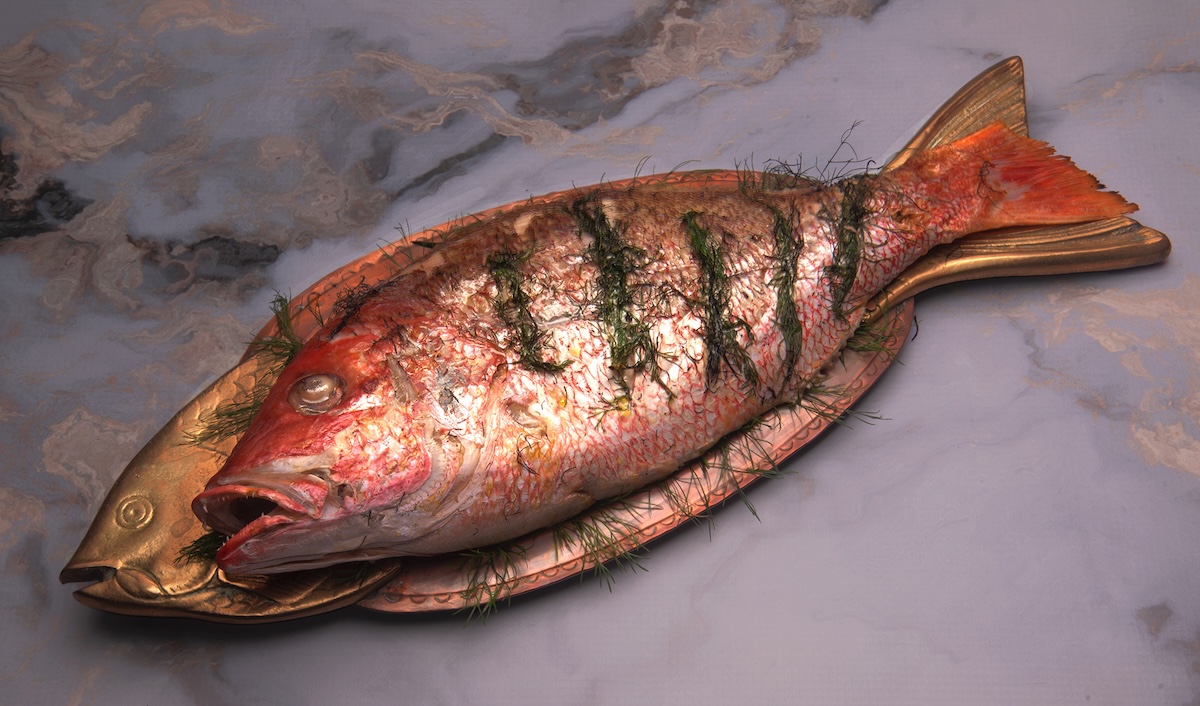 Red Snapper stuffed with herbs, grilled, and served on a fish-shaped platter.