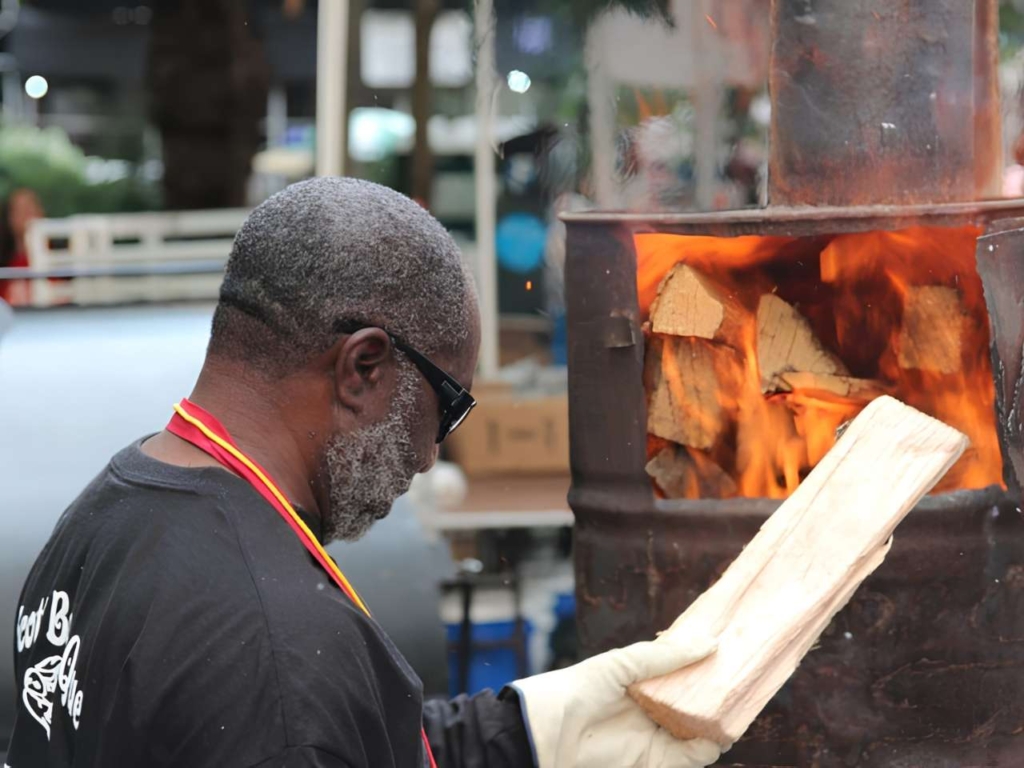 Man putting a piece of wood into a fire