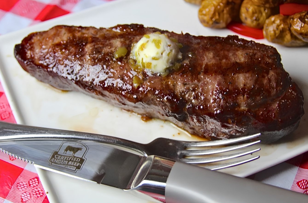 Plated grilled strip steak topped with marrow butter