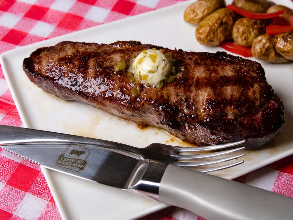 Plated grilled strip steak topped with marrow butter