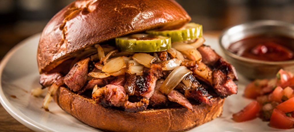 Plated copycat McRib boneless rib sandwich on a pretzel bun.