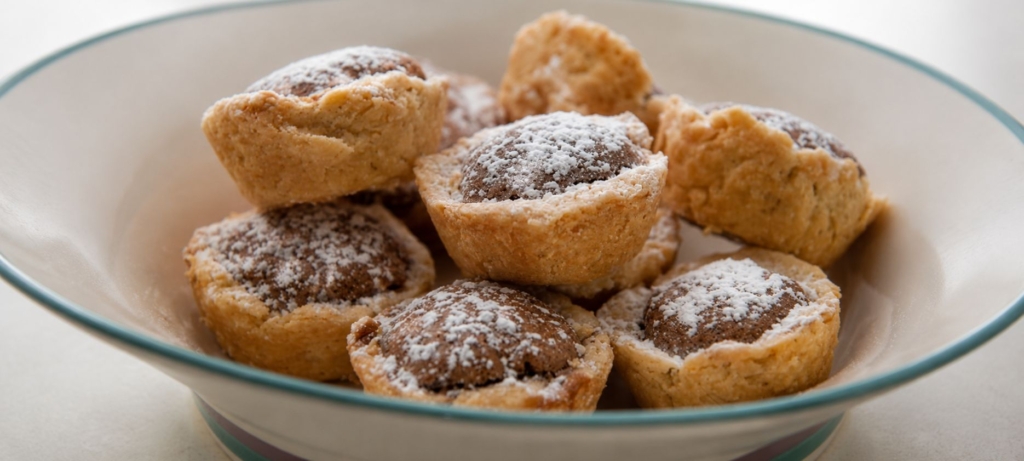 Bowl with several pecan tassies covered in powdered sugar