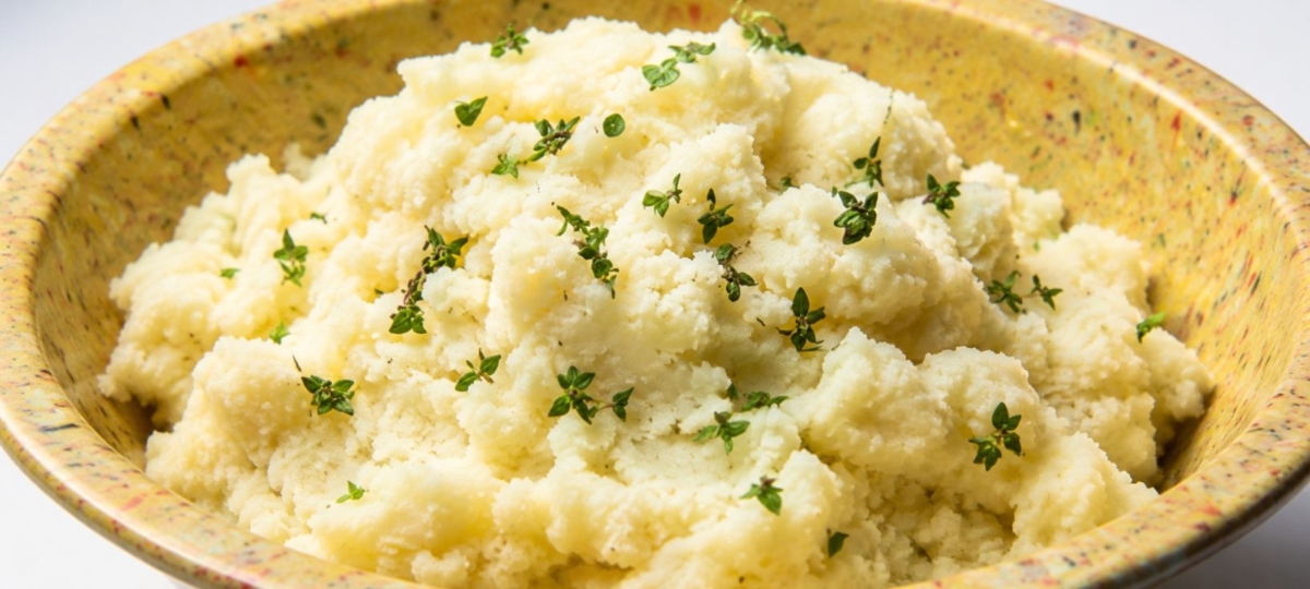 Mashed potatoes in a bowl, topped with thyme leaves.