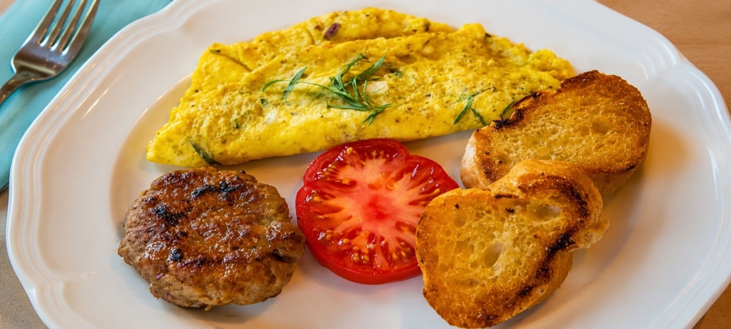 Breakfast sausage on a plate with tomato slice, eggs, and toast