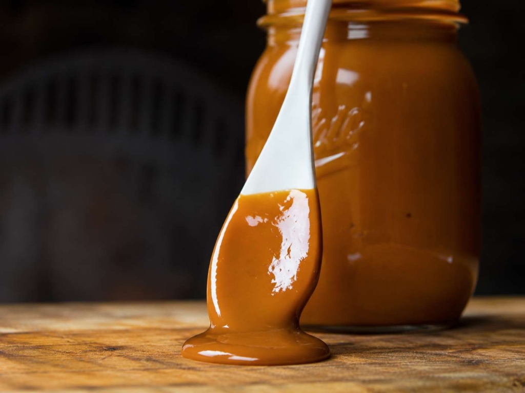 Jar of mustard BBQ sauce with spoon resting on the side