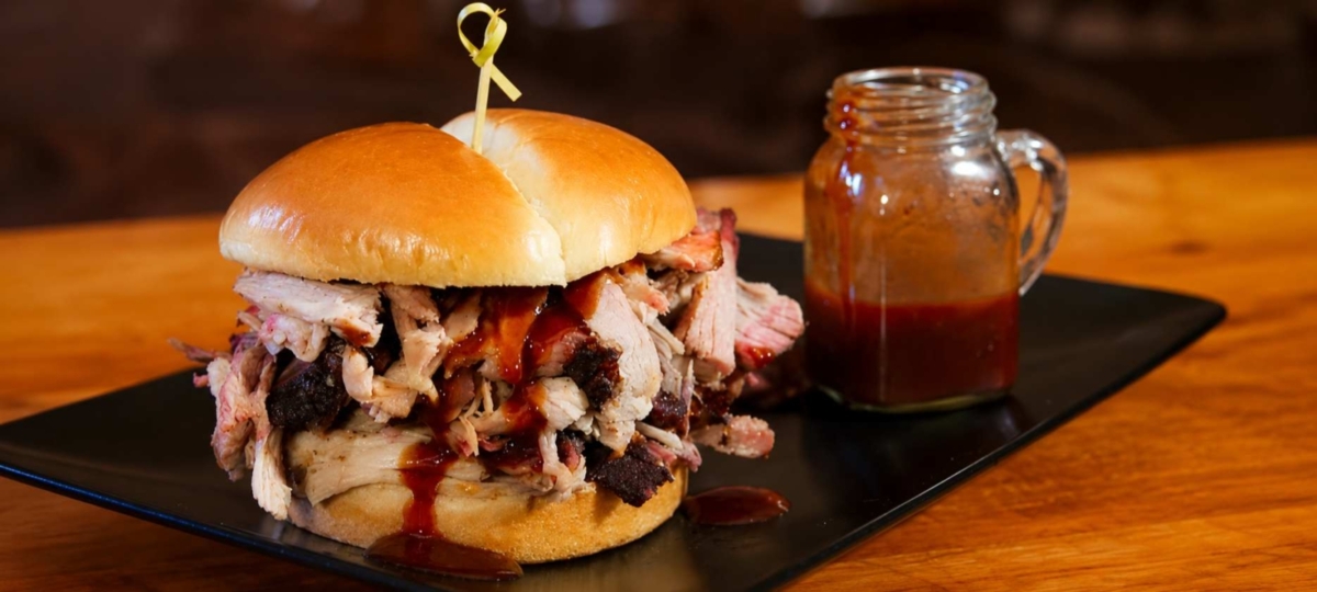 Pulled pork sandwich with sauce in a glass jar
