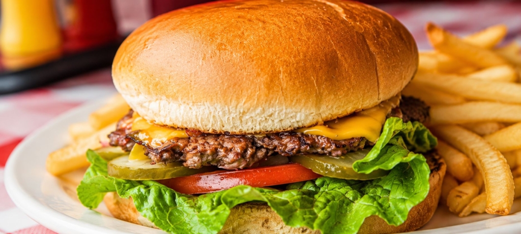 Smash burger with cheese on a plate alongside French fries