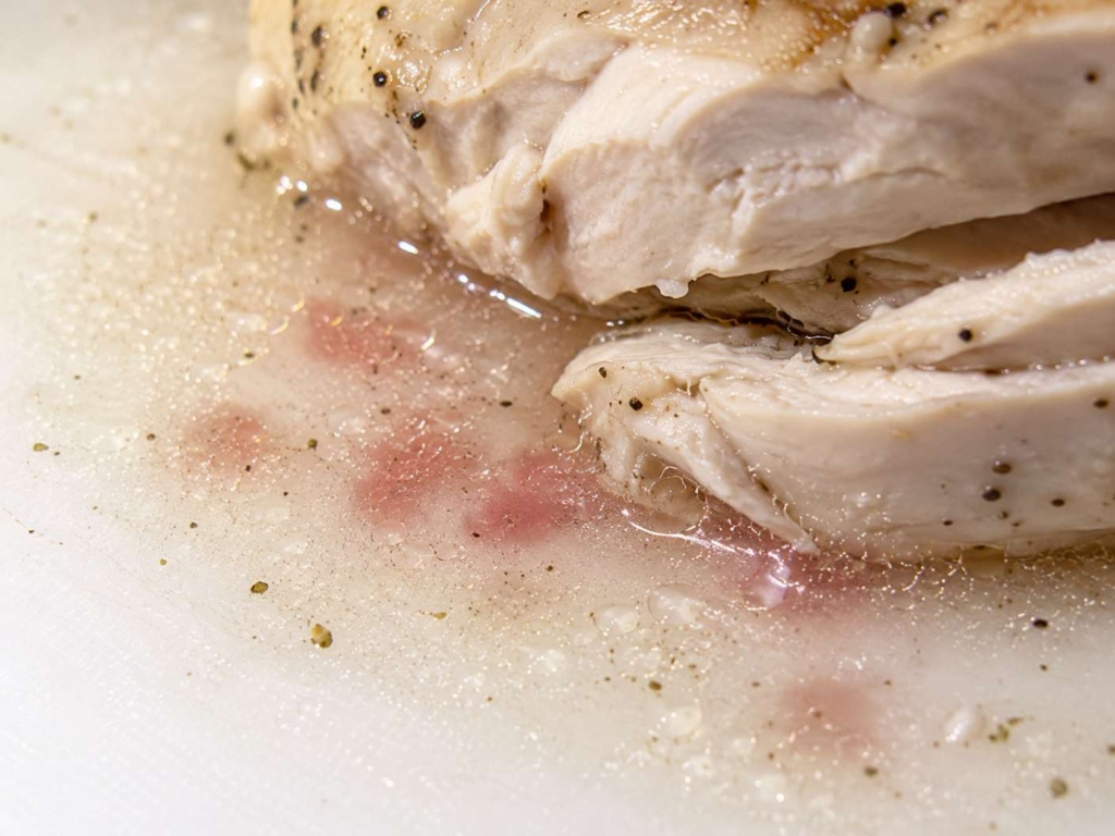 Clear and reddish juices from a piece of chicken.