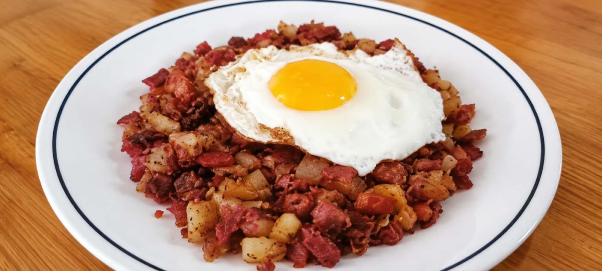 Corned beef hash topped with an egg in a bowl