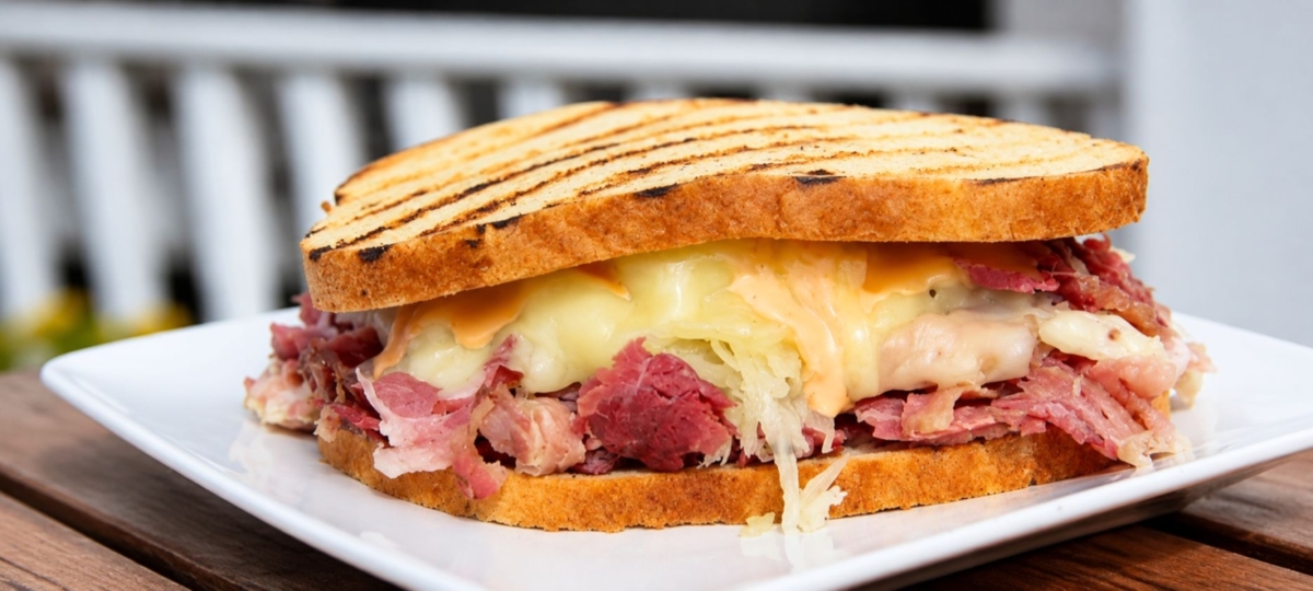 Plated Reuben sandwich with corned beef, cheese, and sauerkraut.