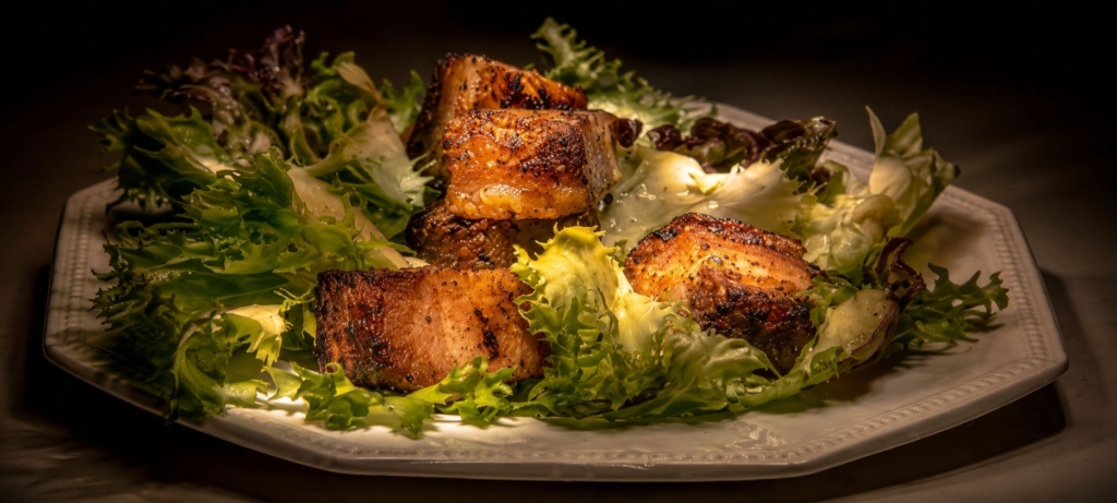 Pork belly croutons on a plated salad.