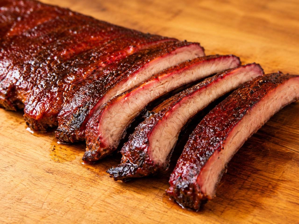 Sliced smoked pork ribs on a wood cutting board.