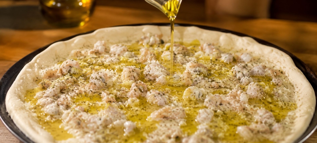 drizzling oil on pepe's white clam pizza.