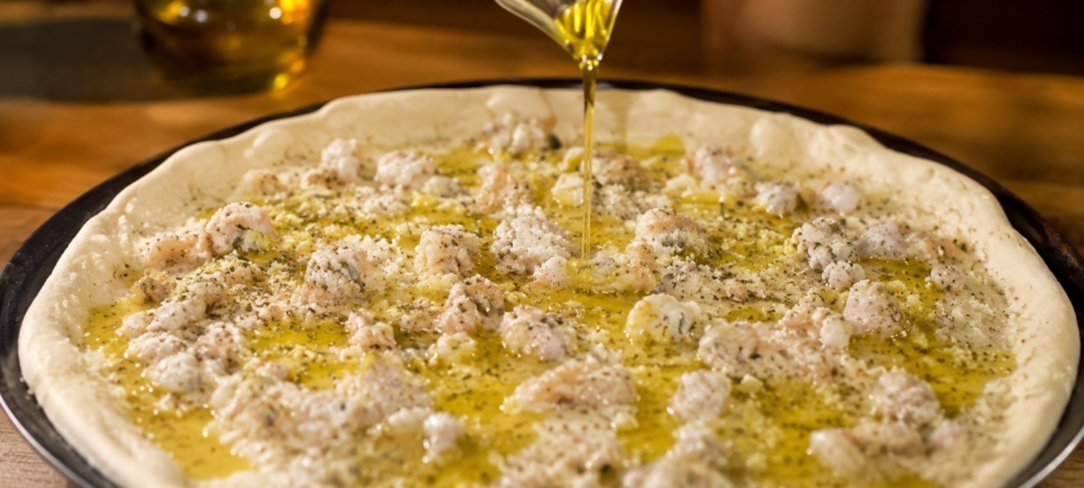 drizzling oil on pepe's white clam pizza.