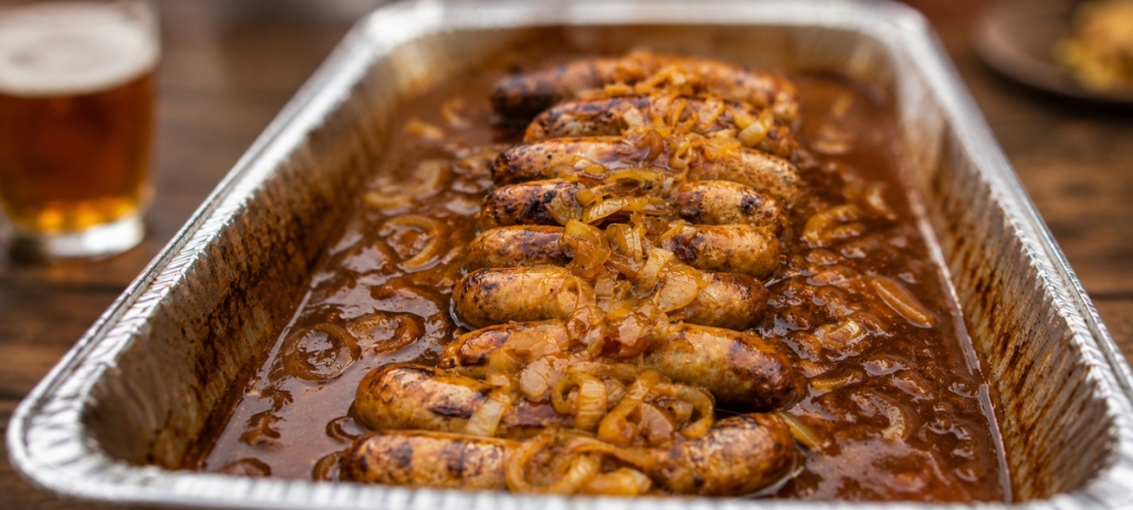 Bratwurst in beer and BBQ sauce liquid with onions