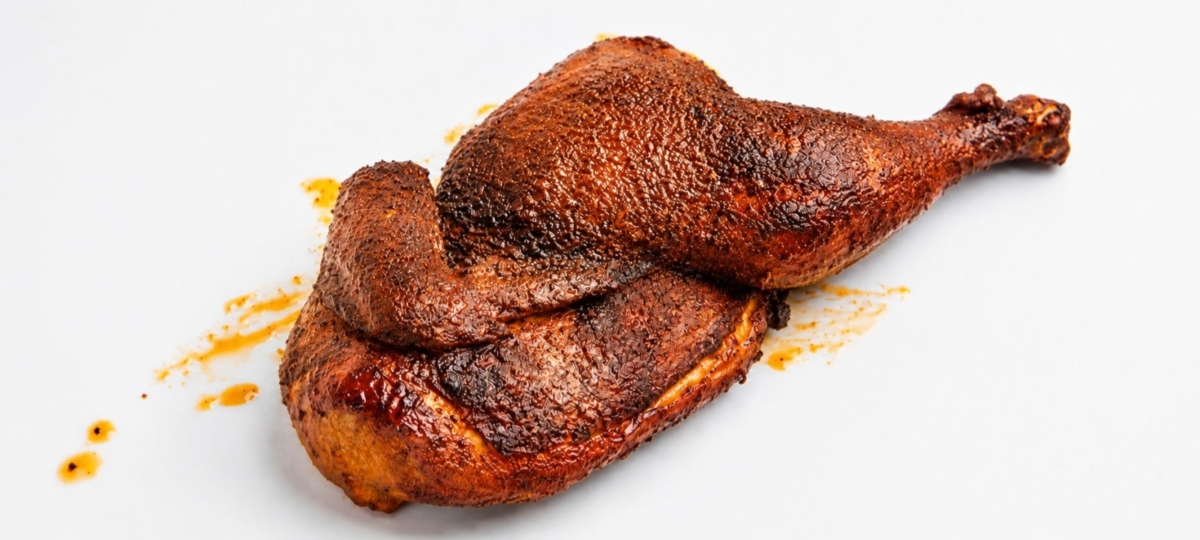 Smoked Georgia brown chicken quarter on a white plate