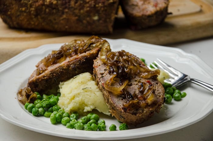 grilled meatloaf on plate with potatoes and peas