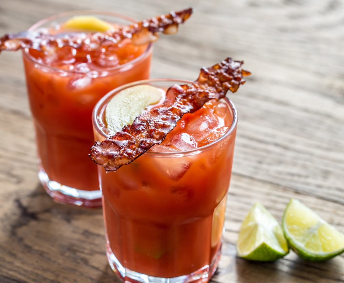 Two bloody mary cocktails garnished with bacon.