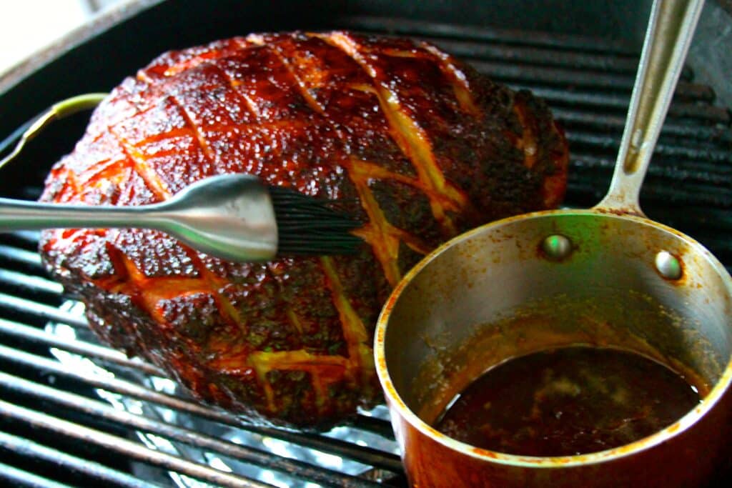 ham on a grill bring brushed with glaze