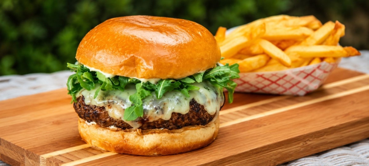 Kangaroo burger topped with arugula and a side of fries.