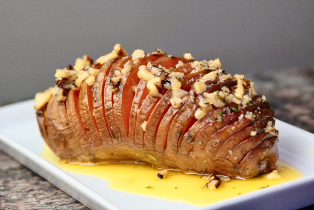 Hasselback sweet potato with maple pecan butter on a plate