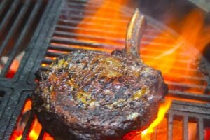 steak on a grill with flames.