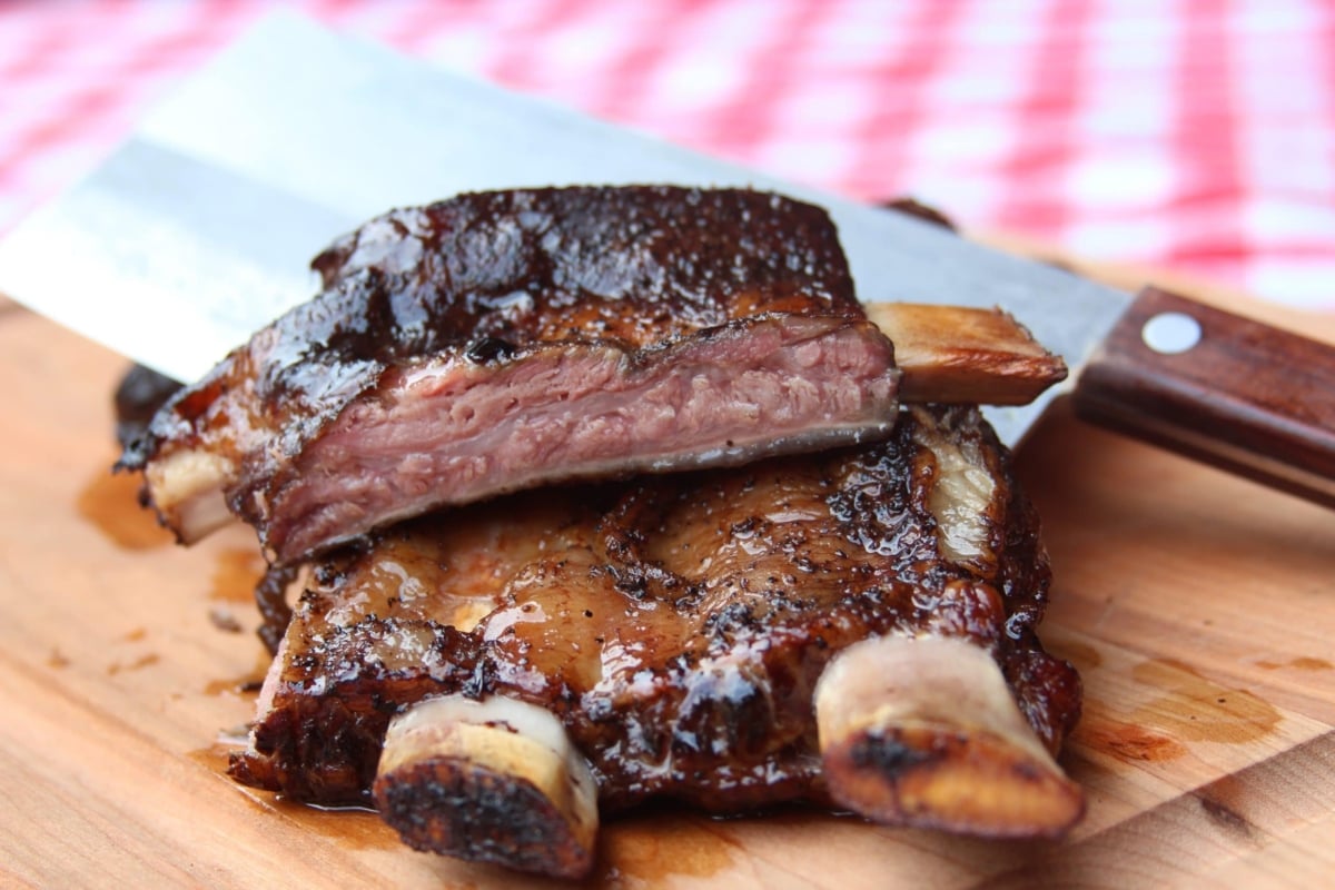 Smoked and sliced beef ribs on cutting board with cleaver