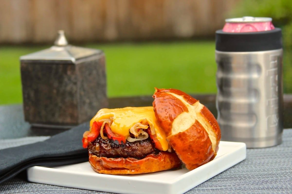 Brat burger with cheese sauce on a pretzel bun