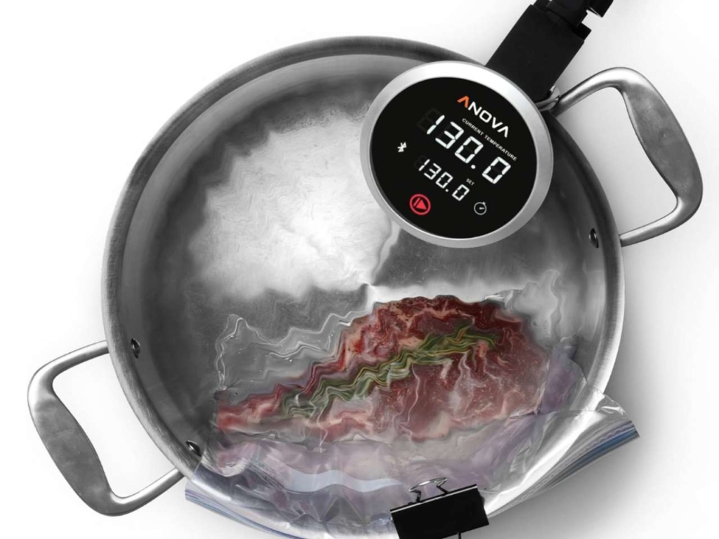 Anova sous vide immersion circulator in a pot with water along with a steak.