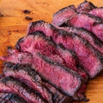 Sliced elk steak on wood cutting board