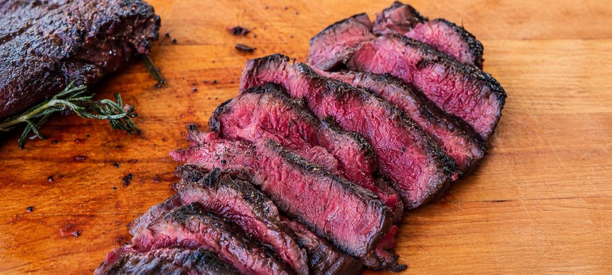 Sliced elk steak on wood cutting board