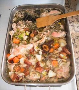 Chopped up turkey carcass, vegetables, and herbs in a drip pan