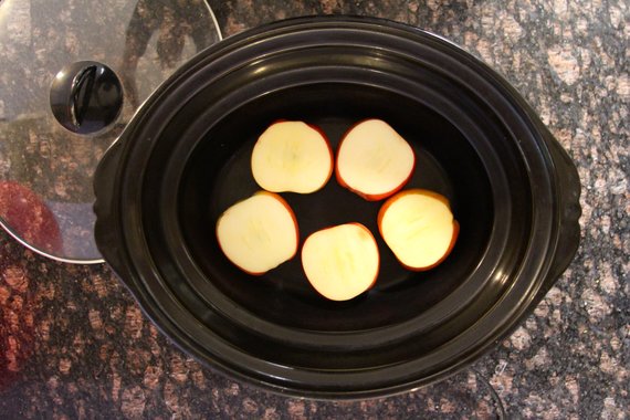 Sliced apples placed at the boom of a slow cooker