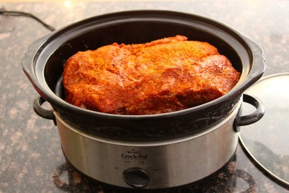 Seasoned pork butt inside of a slow cooker