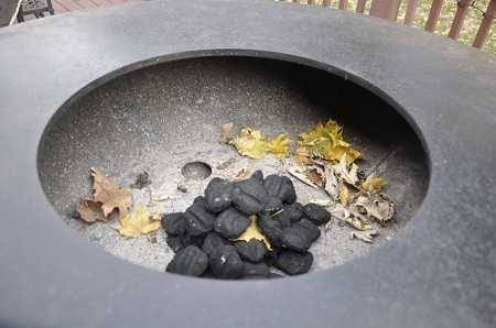 Large round metal bowl with autumn leaves and charcoal inside.