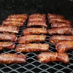 Individual ribs, wrapped in bacon, shine on the grill