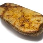Grill marks crisscross a halved baked potato