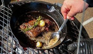 Elk steak being basted in a cast iron skillet