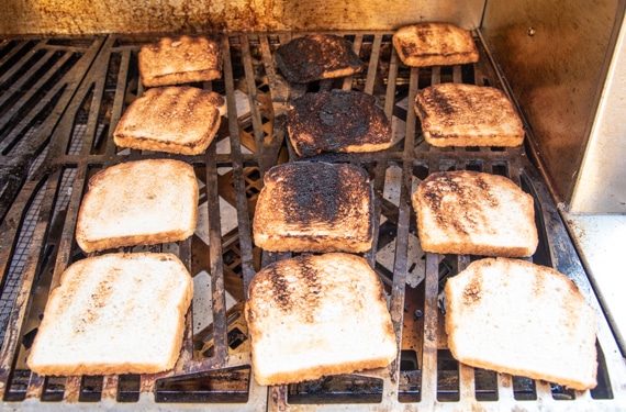 Toasted bread on a cooking grate. The middle pieces are burnt.