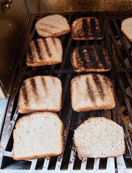 Toasted bread on a cooking grate. The upper right pieces are burnt.