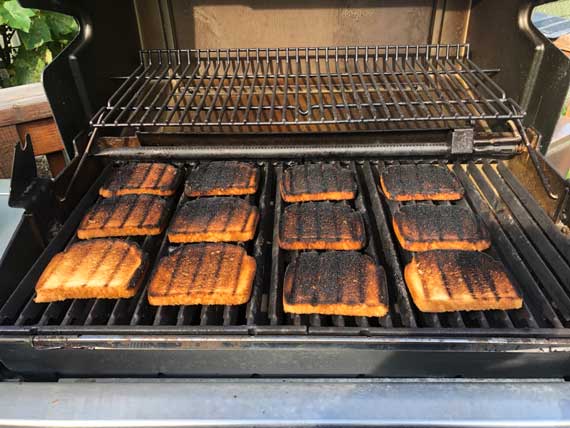 Slices of toasted bread spread across a BBQ grill.