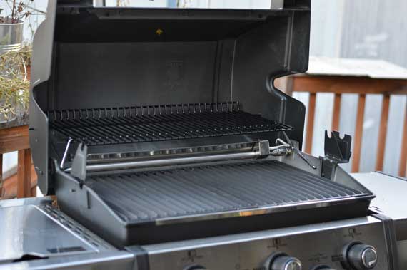 A gas grill with the lid up.