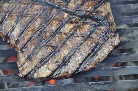Close up of steak sizzling on a gas grill. The grill marks are deep and dark.