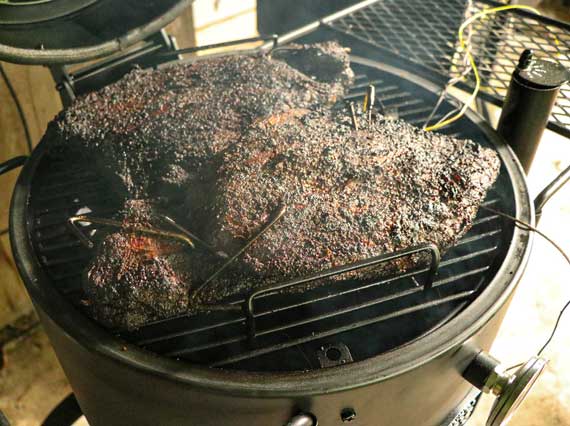 Large hunk of smoked meat covering a round grill.