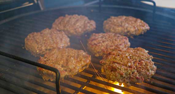 Hamburgers sizzling on a grill.