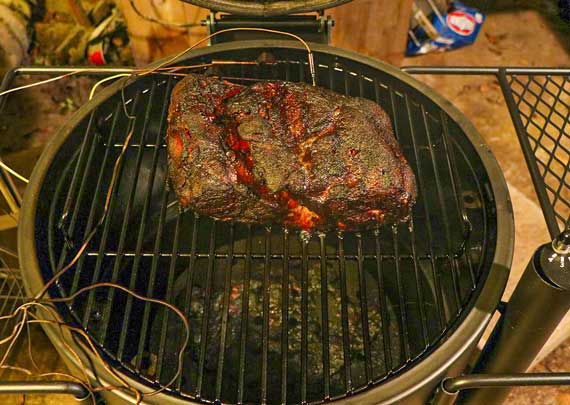 Large hunk of smoked meat on a round grill.